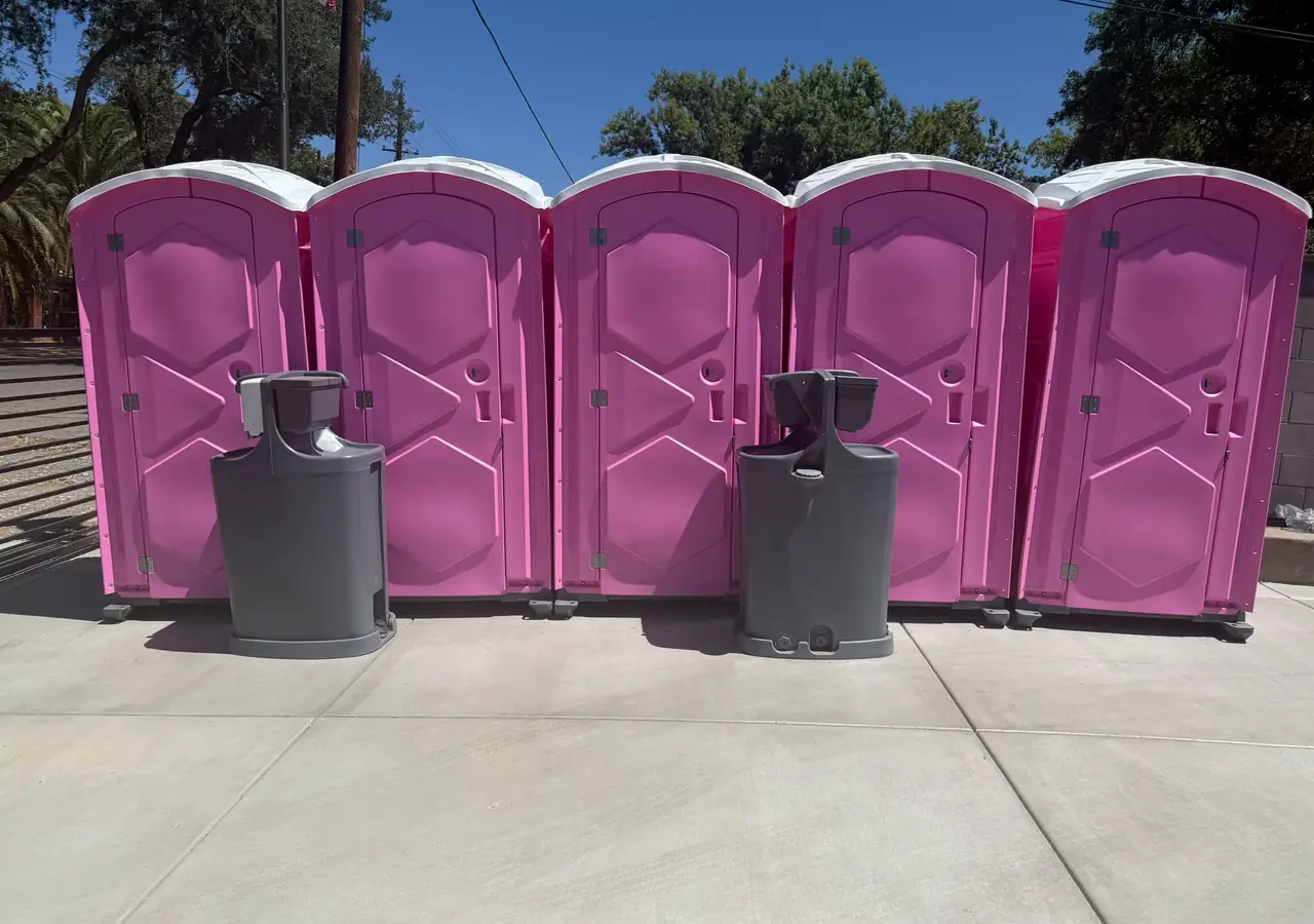 Five porta potties with two hand-wash stations set up for an event