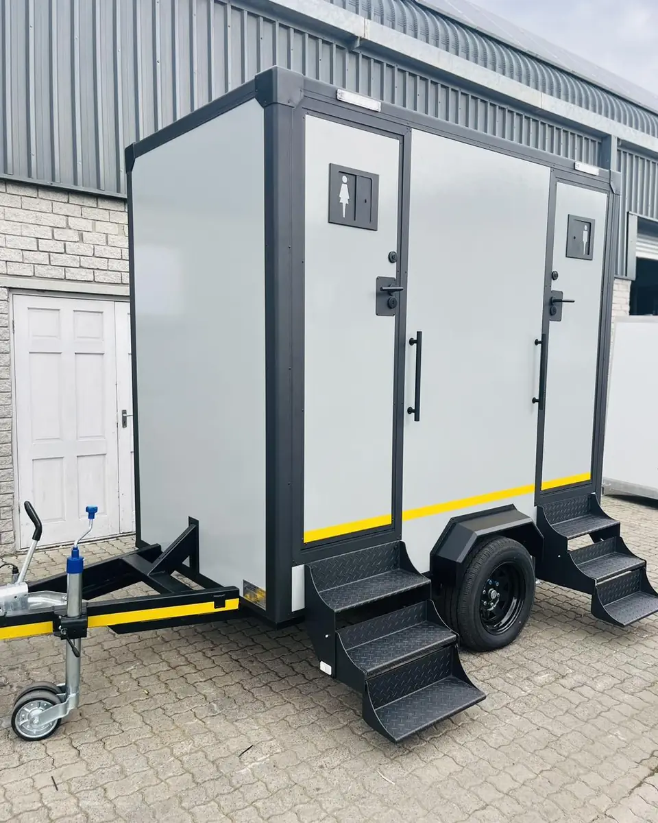 Two-stall restroom trailer with fold-down steps on a paved lot